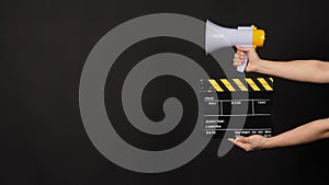 Black and yellow Clapperboard or movie clapper board and Megaphone with man hand in yellow color isolated on black background