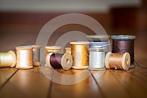Black, Yellow, Gold, Silver, White, and Beige Thread on Wooden Spools Standing on Wooden Planks