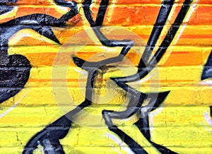 Black and yellow graffiti detail on a brick wall