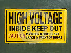 Black on yellow high voltage warning sign on side of transformer vault.