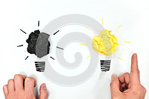 Black and yellow light bulb crumpled paper with hands in white background. Creativity, bright ideas and new innovation concept.