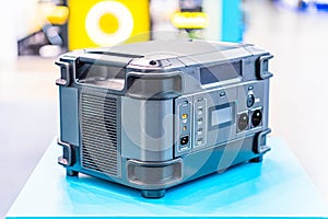 A black and yellow power generator with heavy-duty wheels, visible vents, and inputoutput panels is situated on a blue warehouse