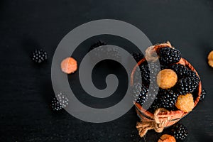 Black and yellow raspberries in a wooden basket on background. Frame. Copy space. Top view.