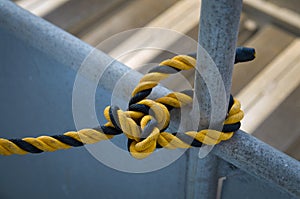 Black and yellow rope tied to an iron bar. Knots on the iron beam