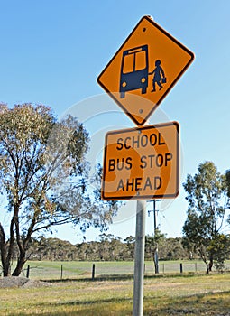 Black and yellow school bus stop ahead sign