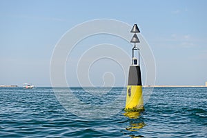 black and yellow sea buoy bobs on the waves