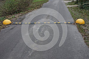 Black yellow speed bump on gray dirty asphalt road