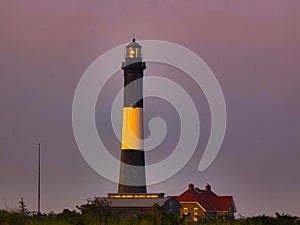 Black and yellow Tybee Island Light Station & Museum on purple sunset sky background in Georgia