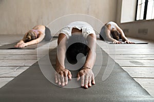 Black yogi woman and group of people doing Balasana exercise photo