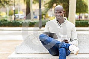 Black young man with tablet computer and take away coffee