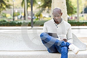 Black young man with tablet computer and take away coffee