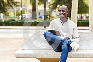 Black young man with tablet computer and take away coffee