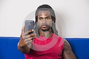 Black young man taking selfie photo on sofa