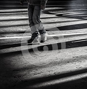 Black young man walking alone in urban city with light and dark shadows - Concept of loneliness, outsider or feeling sad