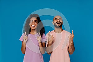 Black young man and woman laughing while pointing fingers upward