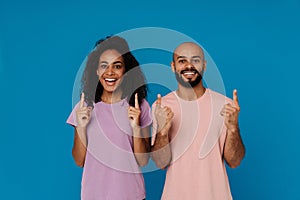 Black young man and woman laughing while pointing fingers upward