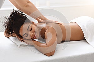 Black young woman enjoying healing back massage at spa