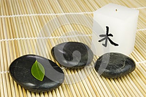 Black zen pebbles, green leaf and japanese candle