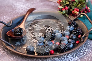 Blackberries and blueberries on a metal platter.