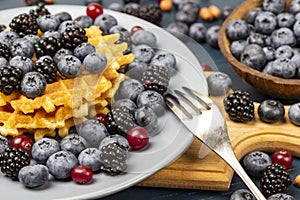 Blackberries, blueberries and waffles in a bowl. Fork on a plate