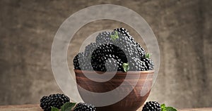 Blackberries and leaves of green mint in bowl. rotation on fabric background