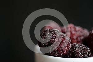 Blackberry berries covered with hoarfrost on a dark background