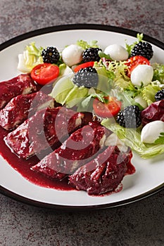 Blackberry Chicken with sweet, tart and savory blackberry butter sauce served with fresh salad closeup in the plate. Vertical