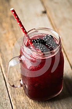 Blackberry cocktail with crushed ice in glass jar on the rustic wooden background. Selective focus. Shallow depth of field