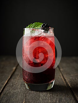 Blackberry cocktail with crushed ice on the rustic wooden background. Selective focus. Shallow depth of field