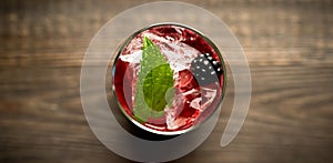 Blackberry cocktail with crushed ice on the rustic wooden background. Selective focus. Shallow depth of field