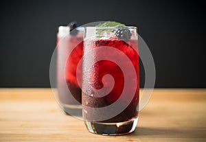 Blackberry cocktail with crushed ice on the rustic wooden background. Selective focus. Shallow depth of field