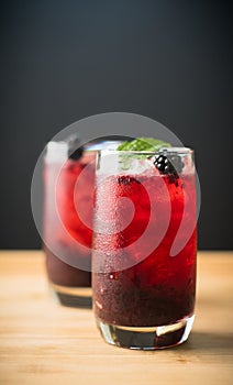 Blackberry cocktail with crushed ice on the rustic wooden background. Selective focus. Shallow depth of field