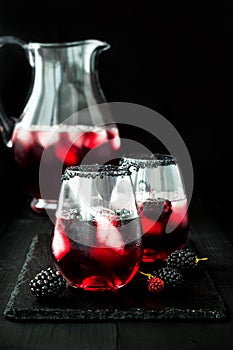 Blackberry drink in glasses with black sugar rim for fall and halloween parties.