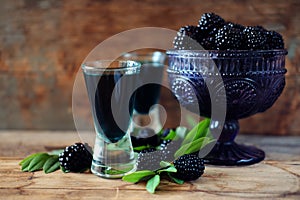 Blackberry fruit liqueur in two shot glasses with berries and gr