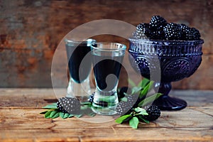 Blackberry fruit liqueur in two shot glasses with berries and gr