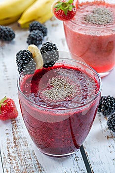 Blackberry and strawberry smoothies garnished with chia seeds and fresh fruit.