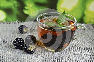 Blackberry tea with fresh picked blackberries in a glass cup on a burlap cloth background.Healthy drink,diet,alternative therapy