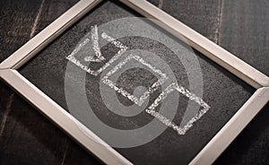 Blackboard with check boxes on chalk board. Hand writing. Dark background