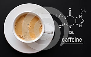 Blackboard with the chemical formula of caffeine, close up cup of fresh coffee on black background. Top view with copy space