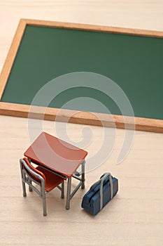 Blackboard, desk, and school bag on wood.
