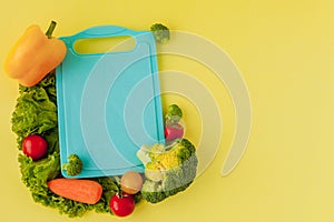 Blackboard with fresh vegetables on yellow background. Concept of Healthy Eating photo