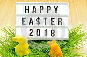 Blackboard with the inscription Happy Easter 2018 in German Happy Easter 2018, dollar sign, bouquet of flowers and Easter bunnies