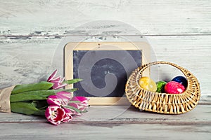 Blackboard with pink tulips and basket with eggs