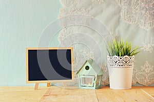 Blackboard with room for text, vintage Flower pot and lantern as a bird house against mint wall and antique lace fabric