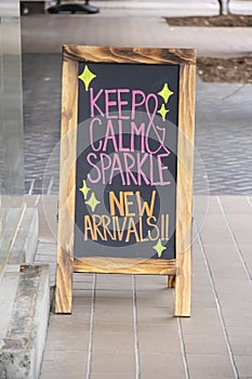 Blackboard sandwich board sign  on sidewalk outside clothing store in neon colors announcing new arrivals - Selective focus