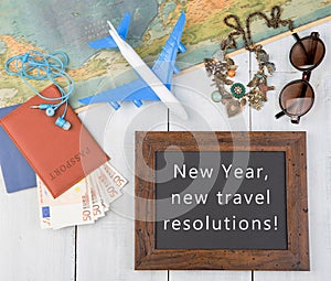blackboard with text "New Year, new travel resolutions!", plane, map, passport, money, sunglasses photo