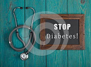 Blackboard with text & x22;STOP diabetes!& x22; and stethoscope on blue wooden background