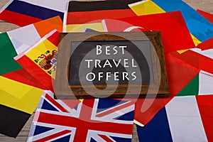 blackboard with text & x22;Best travel offers& x22;, flags of different countries on wooden background