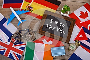 blackboard with text & x22;I love to Travel& x22;, flags of different countries, airplane model, little bicycle and suitcase