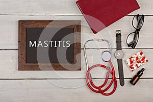 blackboard with text & x22;Mastitis& x22;, book, eyeglasses, watch and stethoscope photo